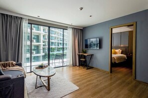 A modern hotel room with a large balcony, a sofa, a small table, and a bed. - Suite Elio 1br | Pools|gym & shuttle to nai harn (Rawai)