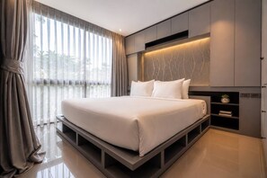 Un dormitorio moderno con una cama grande, estanterías empotradas y vistas a través de cortinas translúcidas.