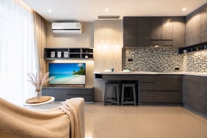 Una cocina moderna con televisor de pantalla plana, armarios oscuros y salpicadero de azulejos.