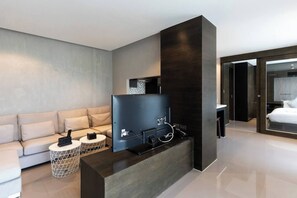 A modern hotel room with a flat-screen TV, a sofa, a coffee table, and a large window. - Suite Nova 2br|rooftop Pool & gym| citygate kamala (Tambon Kammala)