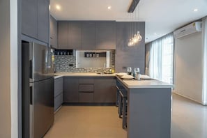 A modern kitchen with a central island, built-in appliances, and a large window providing natural light.