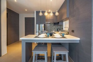 A modern kitchen with a central island, stainless steel appliances, and pendant lighting.