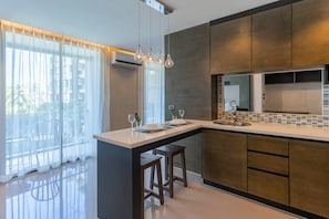 A modern kitchen with a central island, dark cabinetry, and pendant lighting. - Suite Nova 2br|rooftop Pool & gym| citygate kamala (Tambon Kammala)