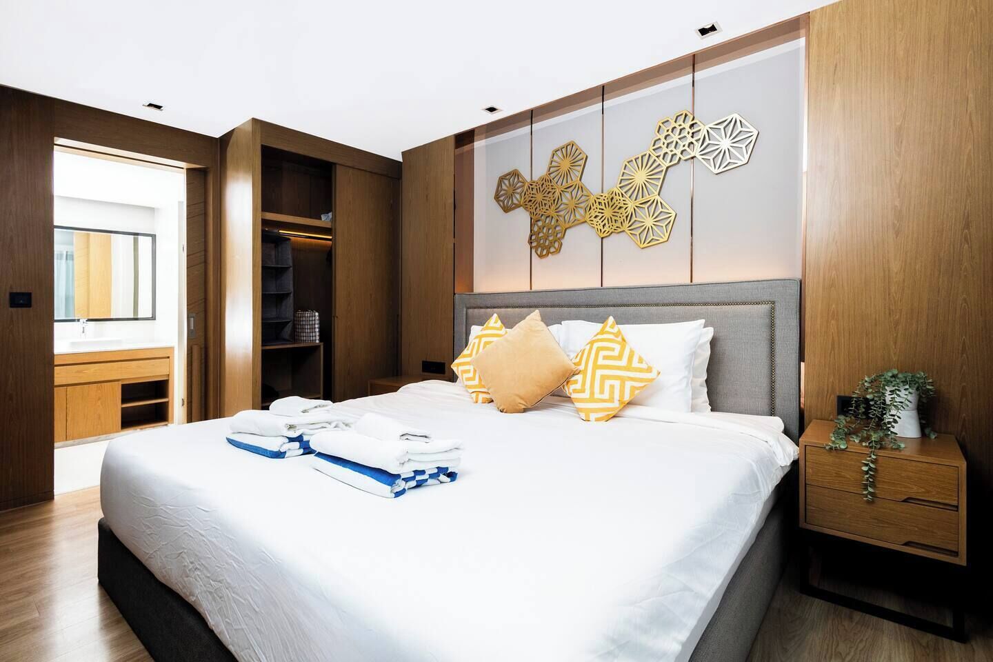 A modern hotel room with a large bed, a wooden wardrobe, and a decorative wall panel.