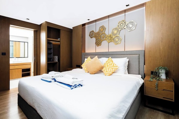 A modern hotel room with a large bed, a wooden wardrobe, and a decorative wall panel.
