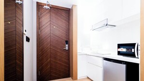 Cozinha moderna com micro-ondas, máquina de lavar louça e porta de madeira com fechadura.