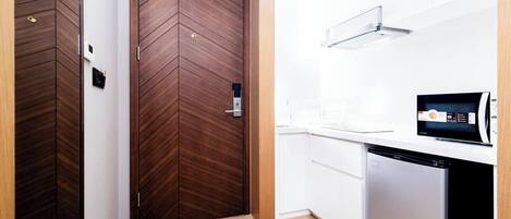 Una cocina moderna con microondas, lavavajillas y una puerta de madera con ojo de cerradura.