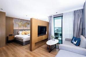 A modern hotel room with a bed, a TV, a sofa, and a balcony with a city view.
