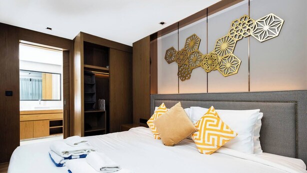 Quarto de hotel com cama, guarda-roupa e um objeto decorativo na parede.
