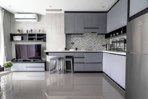 A modern kitchen with a built-in stove, stainless steel appliances, and a tiled backsplash.