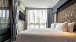 A modern hotel room with a large bed, a flat-screen TV mounted on the wall, and a view of the outdoors through sheer curtains. - Luxury 1br Resort Retreat Property p514 (Tambon Kammala)