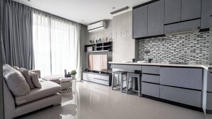 A modern kitchen with a central island, grey cabinetry, and a dining area with a sofa and curtains. - Luxury 1br Resort Retreat Property p514 (Tambon Kammala)