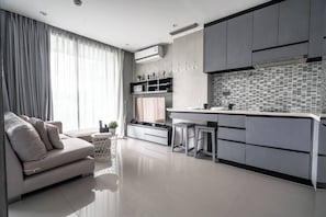 A modern kitchen with a central island, grey cabinetry, and a dining area with a sofa and curtains. - Luxury 1br Resort Retreat Property p514 (Tambon Kammala)
