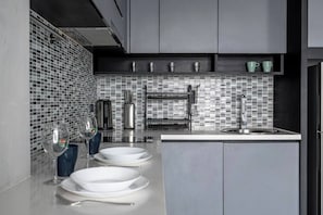 A modern kitchen with a tiled backsplash, stainless steel appliances, and a built-in sink. - Luxury 1br Resort Retreat Property p514 (Tambon Kammala)
