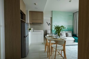 Una cocina moderna con refrigerador integrado, gabinetes blancos y un comedor con mesa dispuesta para dos.