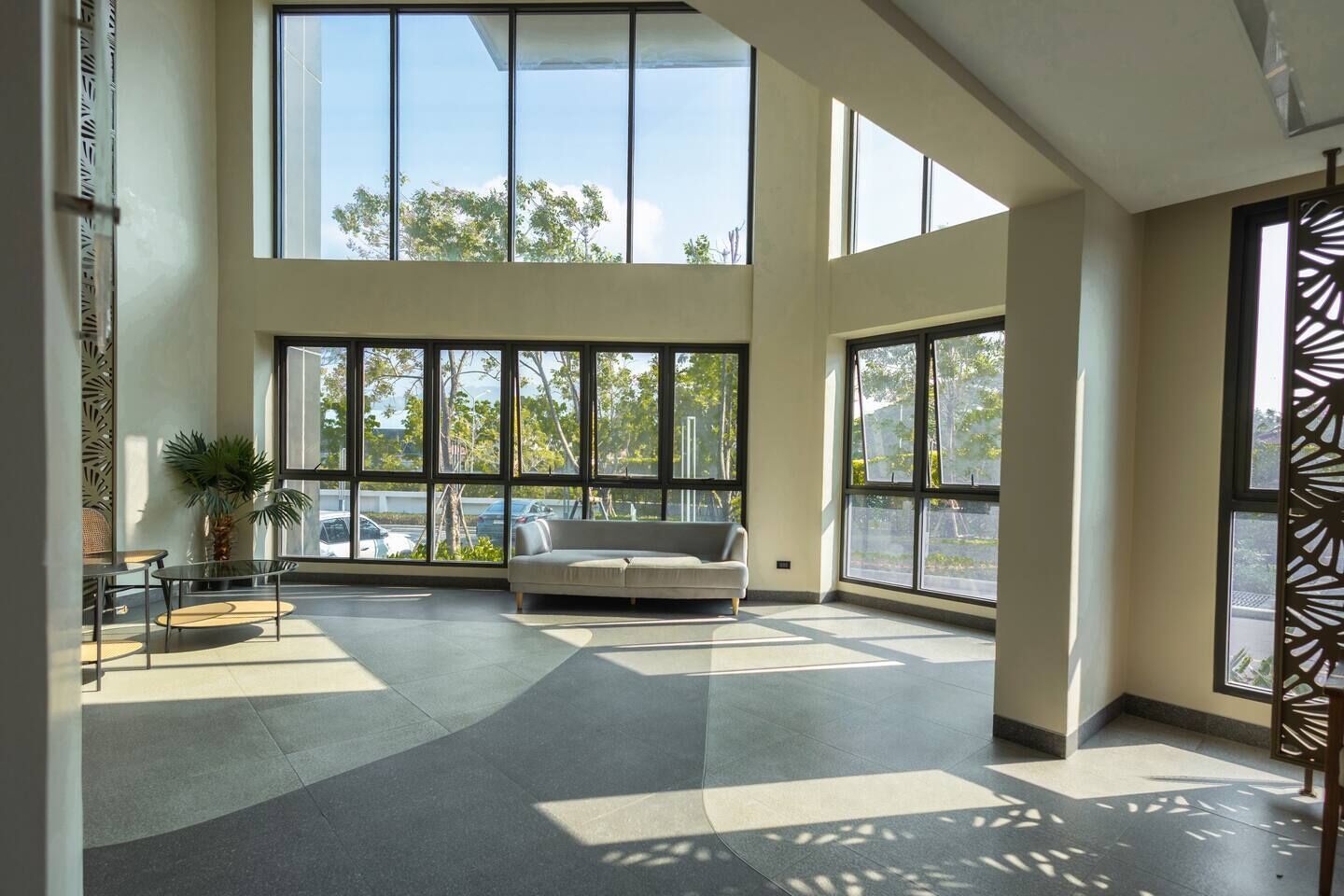 Une pièce spacieuse avec de grandes fenêtres, un canapé et une table basse.