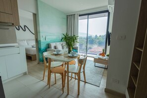 A modern living space with a dining area, a sofa, a balcony with a view, and a kitchen area. - Suite Horizon 2br|rooftop|laguna Skypark Bang tao (Choeng Thale)