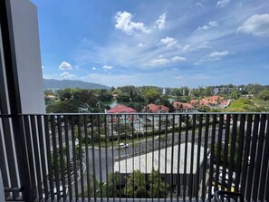 A balcony with a view of a road, buildings, and greenery.