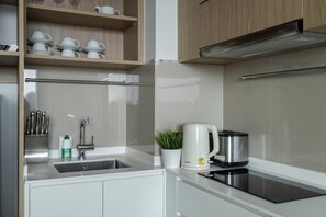 Een moderne keuken met witte kasten, een roestvrijstalen spoelbak, een waterkoker en een broodrooster.