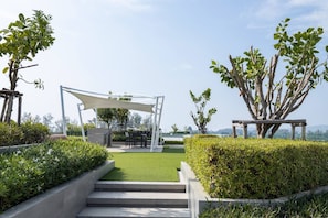 A garden with a pergola, seating area, and a view of the landscape.