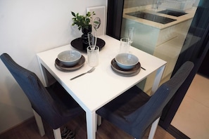 A dining table set with two bowls, two glasses, a fork, and a potted plant.