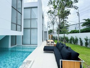 Un área de piscina moderna al aire libre con una zona de estar integrada.