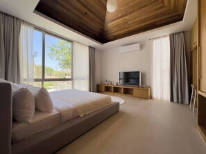A modern bedroom with a large bed, a television, and a wooden ceiling.