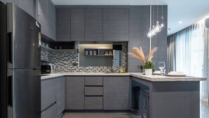 Una cocina moderna con armarios oscuros, un salpicadero azulejado y una isla integrada con pileta y encimera.