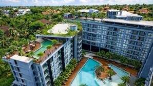 Un hotel de gran altura con varios balcones, una piscina en la azotea y una piscina grande.