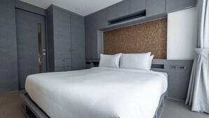 Un dormitorio moderno con una cama grande, armario empotrado y cabecero estampado.