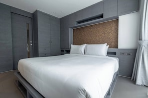 A modern bedroom with a large bed, built-in wardrobe, and a patterned headboard. - Suite Altair 2br|pool & Rooftopbar|citygate kamala (Rawai)