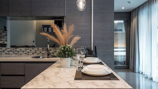 Una cocina moderna con una isla de mármol, iluminación colgante y vista al área de estar.