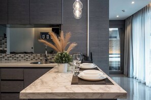 Una cocina moderna con una isla de mármol, iluminación colgante y vista al área de estar.