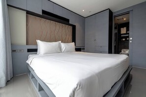 A modern bedroom with a large bed, built-in wardrobe, and a vanity with a mirror.
