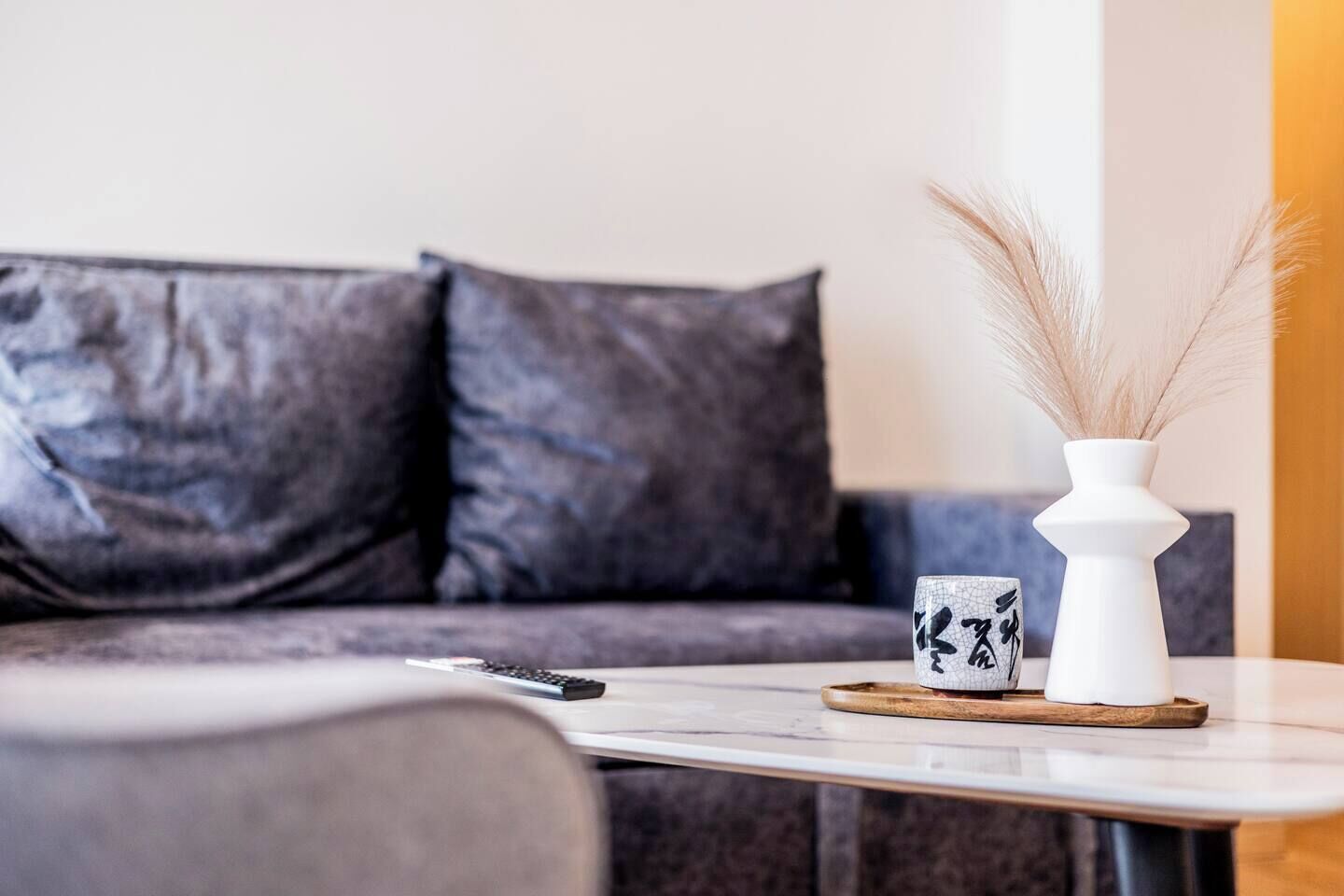 Un salon moderne avec un canapé, une table basse et un vase décoratif contenant des plantes séchées.