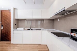 Une cuisine moderne avec des meubles blancs, un évier en acier inoxydable et une cuisinière encastrée.