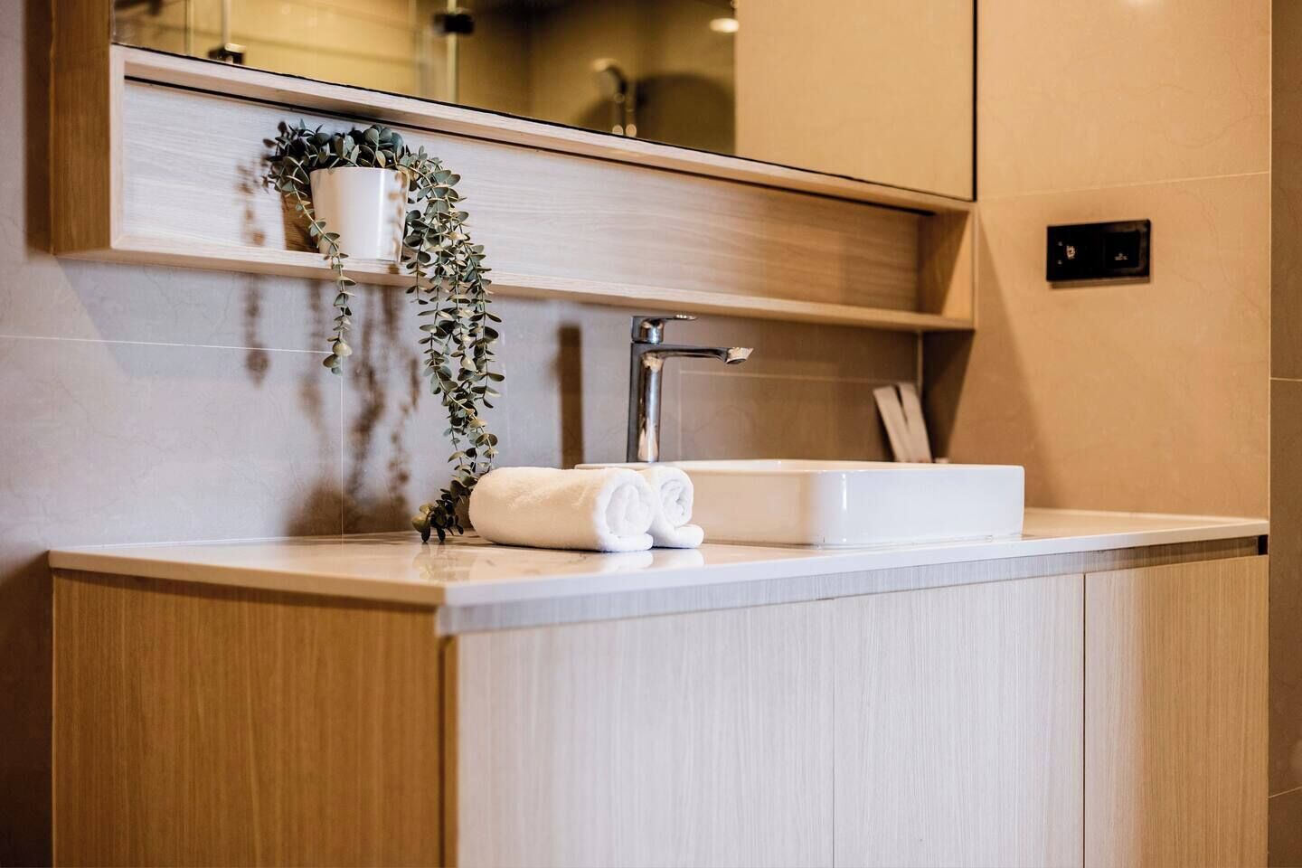 Une salle de bain moderne avec un meuble-lavabo en bois, un lavabo blanc et un miroir au-dessus.