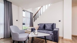 En moderne stue med en grå sofa, en grå lænestol og et lille hvidt bord med en vase.