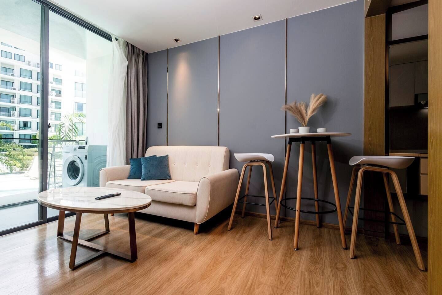 Uma sala de estar moderna com um sofá, uma mesa de centro redonda e dois banquetas.