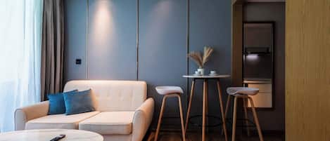 Una sala moderna con un sofá, una mesita redonda y dos taburetes de bar.
