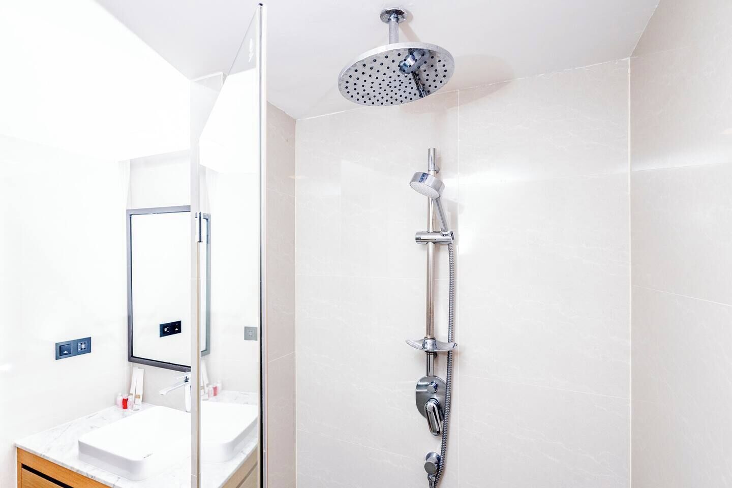 Un bagno moderno con box doccia in vetro, soffione a mano e pannello comandi a parete.