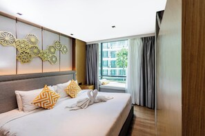 A hotel room with a large bed, a view of the city, and a decorative wall panel. - Suite Aluna 1br | Pools & shuttle to nai harn (Rawai)