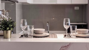 A modern kitchen with white cabinets, a marble countertop, and a small potted plant. - Suite Nami 1br | Pools|gyms & shuttle to nai harn (Rawai)