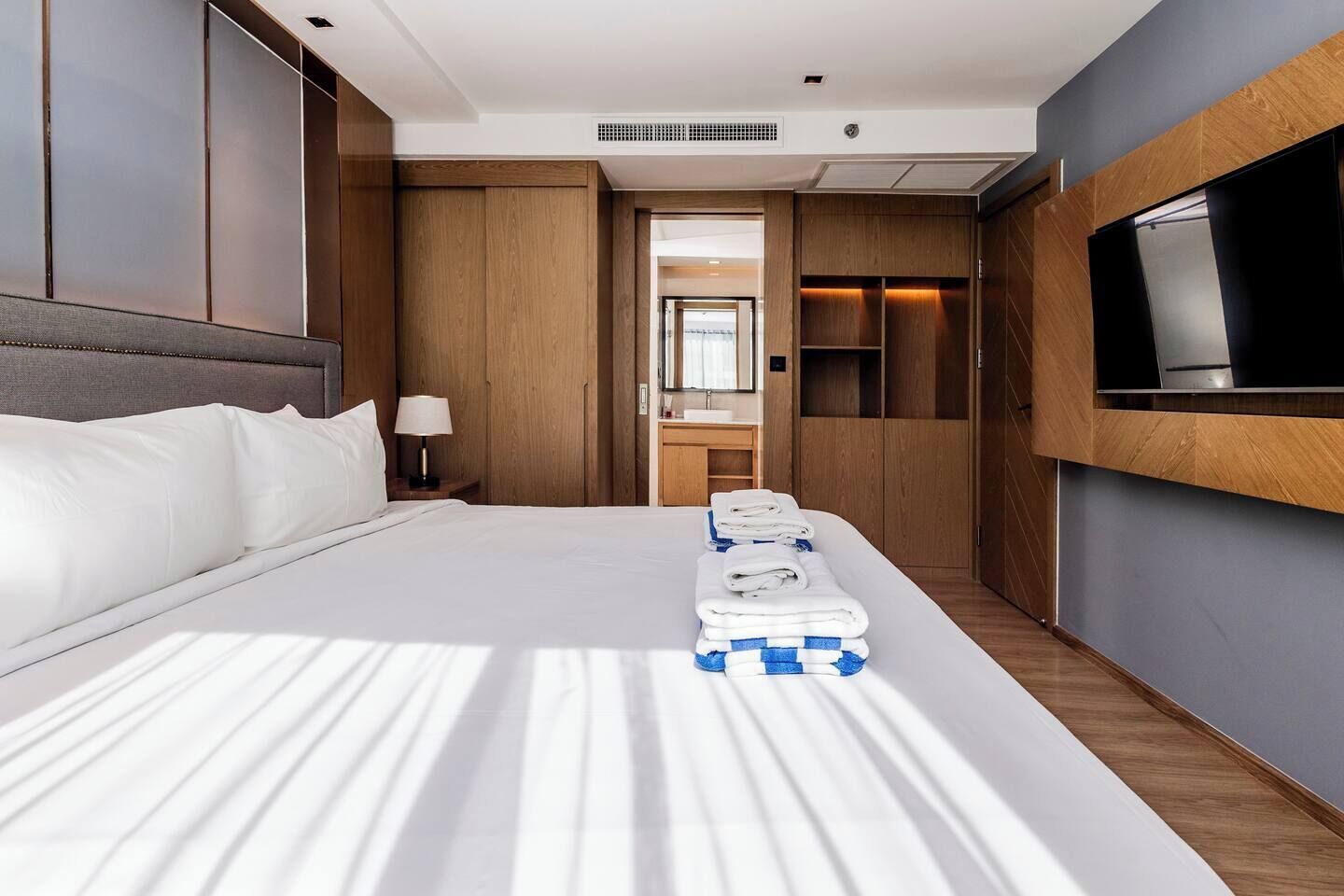 A hotel room with a large bed, a TV mounted on the wall, and a mirror above the bed.