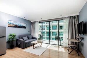 A modern living room with a sofa, coffee table, and a large window with curtains.