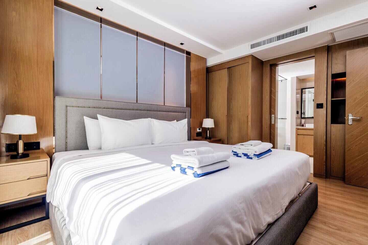 Une chambre d’hôtel avec un grand lit, une armoire en bois, des tables de chevet et un miroir.