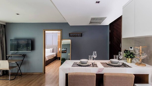 A modern hotel room with a dining area, a bed, a TV, and a bathroom visible through an open door. - Suite Nami 1br | Pools|gyms & shuttle to nai harn (Rawai)