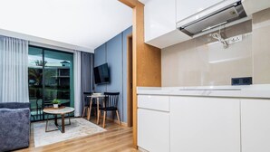 Una cocina moderna con armarios blancos, estufa integrada y televisor de pantalla plana sobre la encimera.