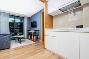 Una cocina moderna con armarios blancos, estufa integrada y televisor de pantalla plana sobre la encimera.