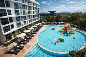 Un hôtel doté d’une piscine avec un toboggan et un espace de jeux, entouré de chaises longues et de parasols.